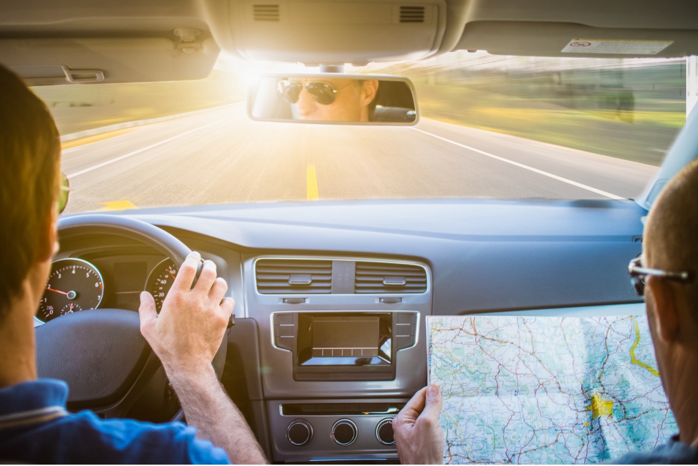 Two men in a rental car driving on a road trip