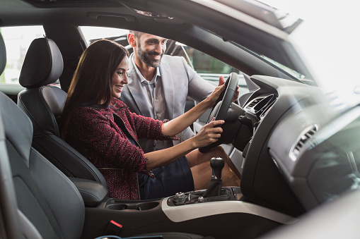 woman inspecting a new car at dealership