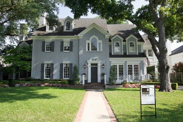 large light blue house under the shade of two large trees